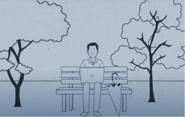 A person sitting on a bench and working on a laptop
